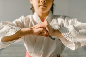 Close-up of a young martial artist in a taekwondo uniform, performing a hand gesture.
