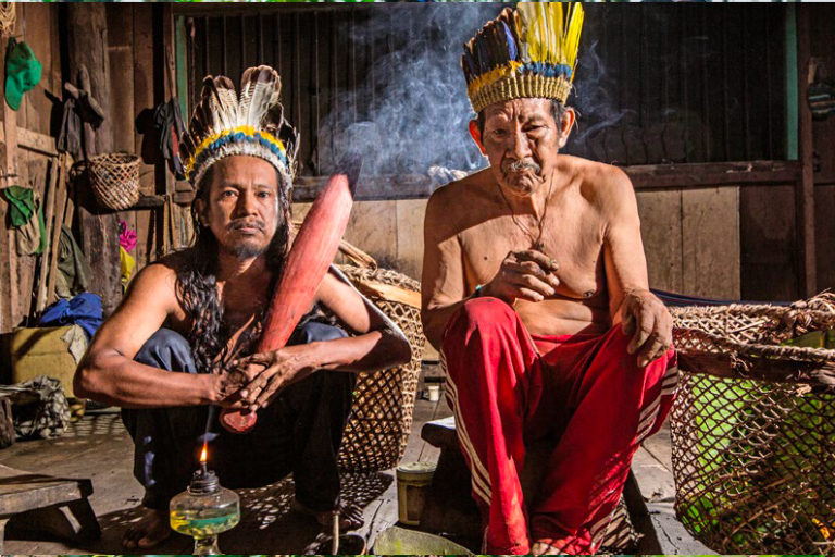 El abuelo Marcelino y su hijo, pueblo indígena en Araracuara, sosteniendo el mambe y ambil provenientes de plantas sagradas de la región en el departamento de Caquetá en la Amazonía colombiana. Foto: Informe Un Clima Peligroso.